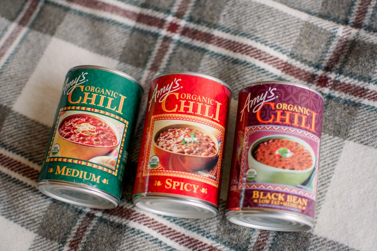 Three cans of Amy's Organic Chili on a checkered cloth surface. 