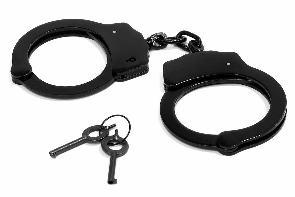 Black handcuffs and handcuffs keys on a white background. 