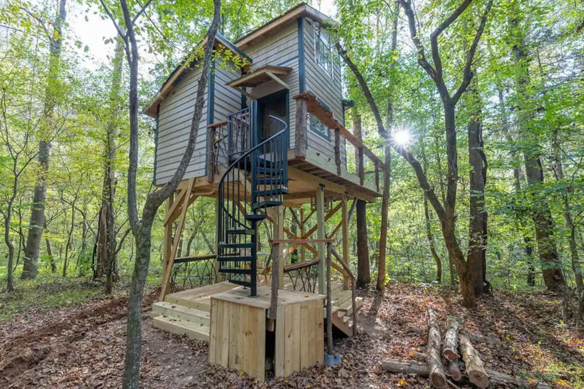 A view of the Luxury Treehouse with a Hot Tub from the outside surrounded by trees.