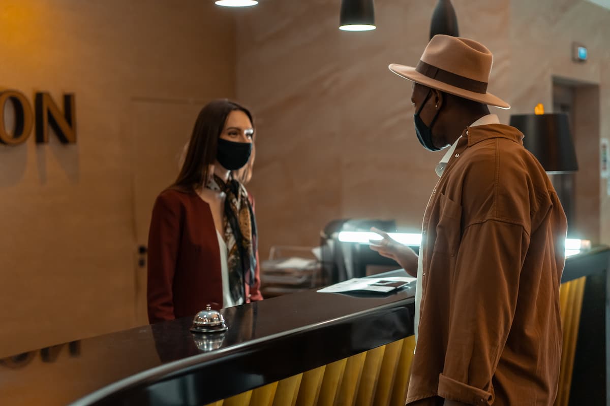 Man talking to the woman at the front desk. 