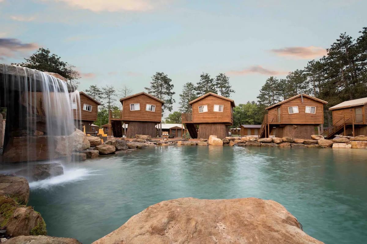 Wooden cabins in Natura Treescape Resort nestled around a lagoon.