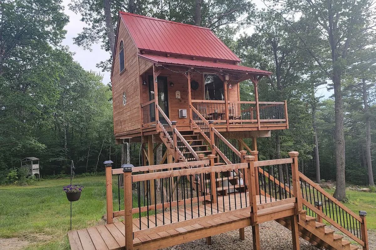 Treehouse with a porch and a long set of stairs.