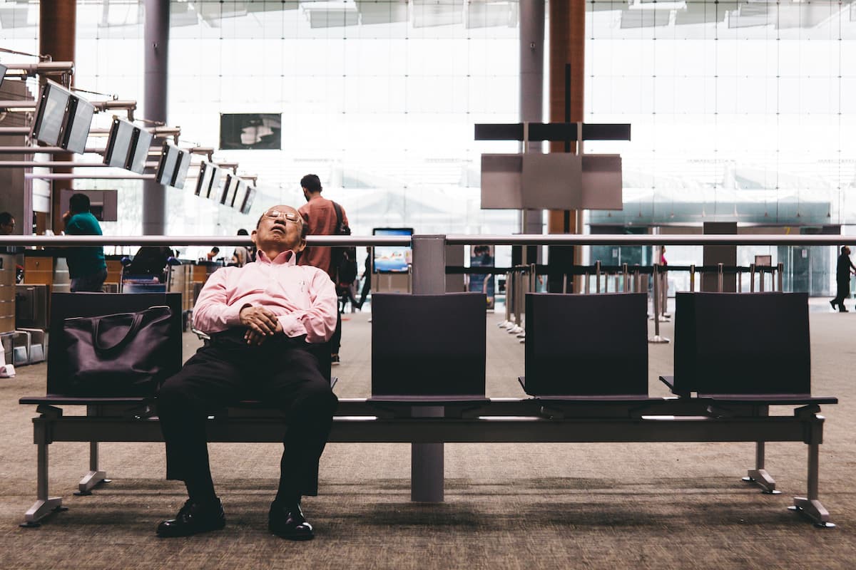 An old man sleeping on a gang chair at the airport. 