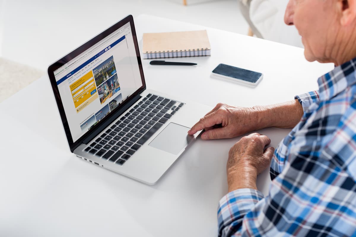 An old man using Booking.com on a laptop. 