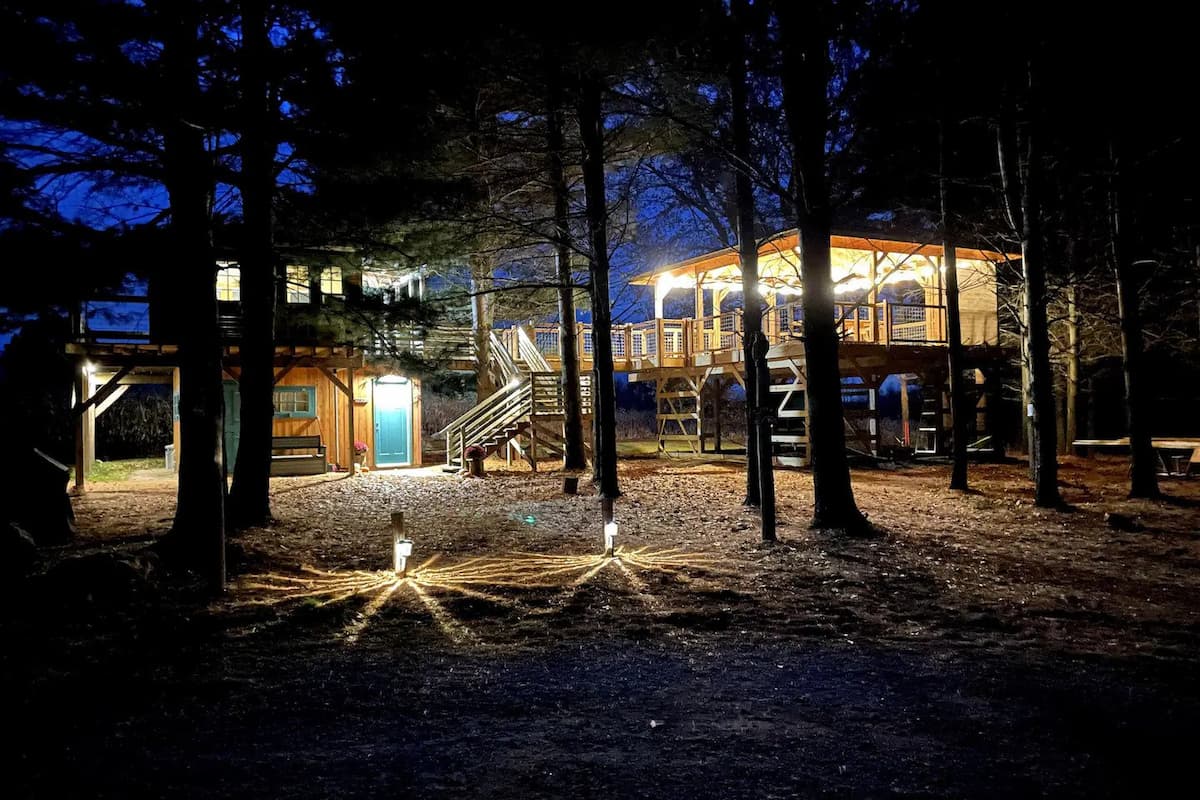 The cabins hover above the ground with the lights on at nighttime. 