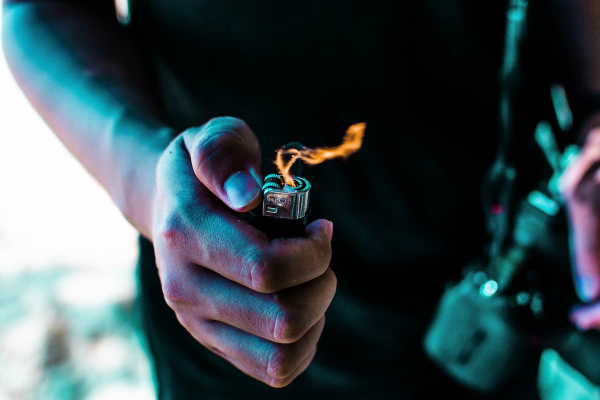 Cropped photo of a person holding a lighted lighter. 