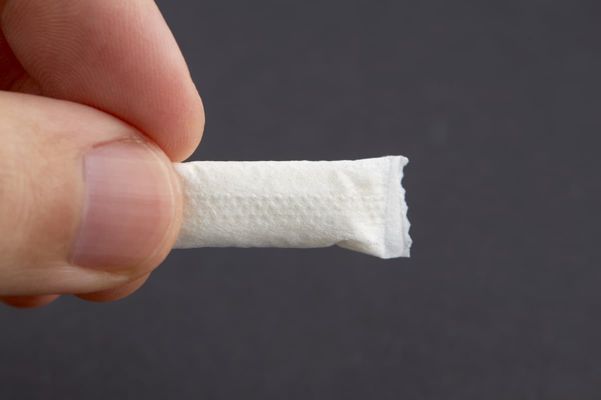 Close-up photo of a person's hand holding a nicotine pouch. 