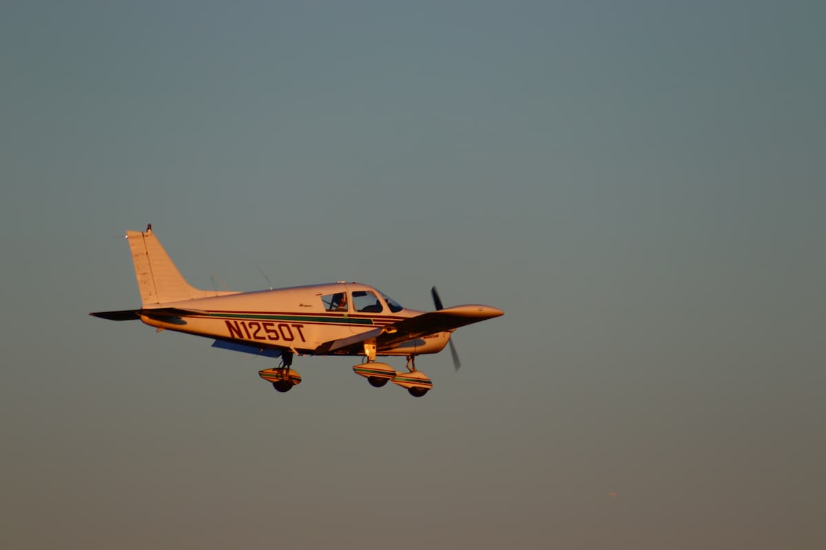 A single engine plane flying in the sky during sunset. 