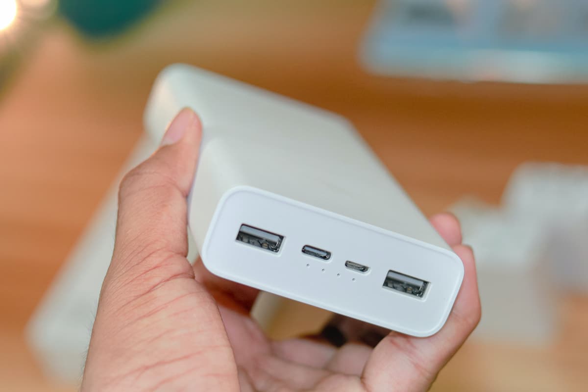 Close-up shot of a person's hand holding a white portable charger. 