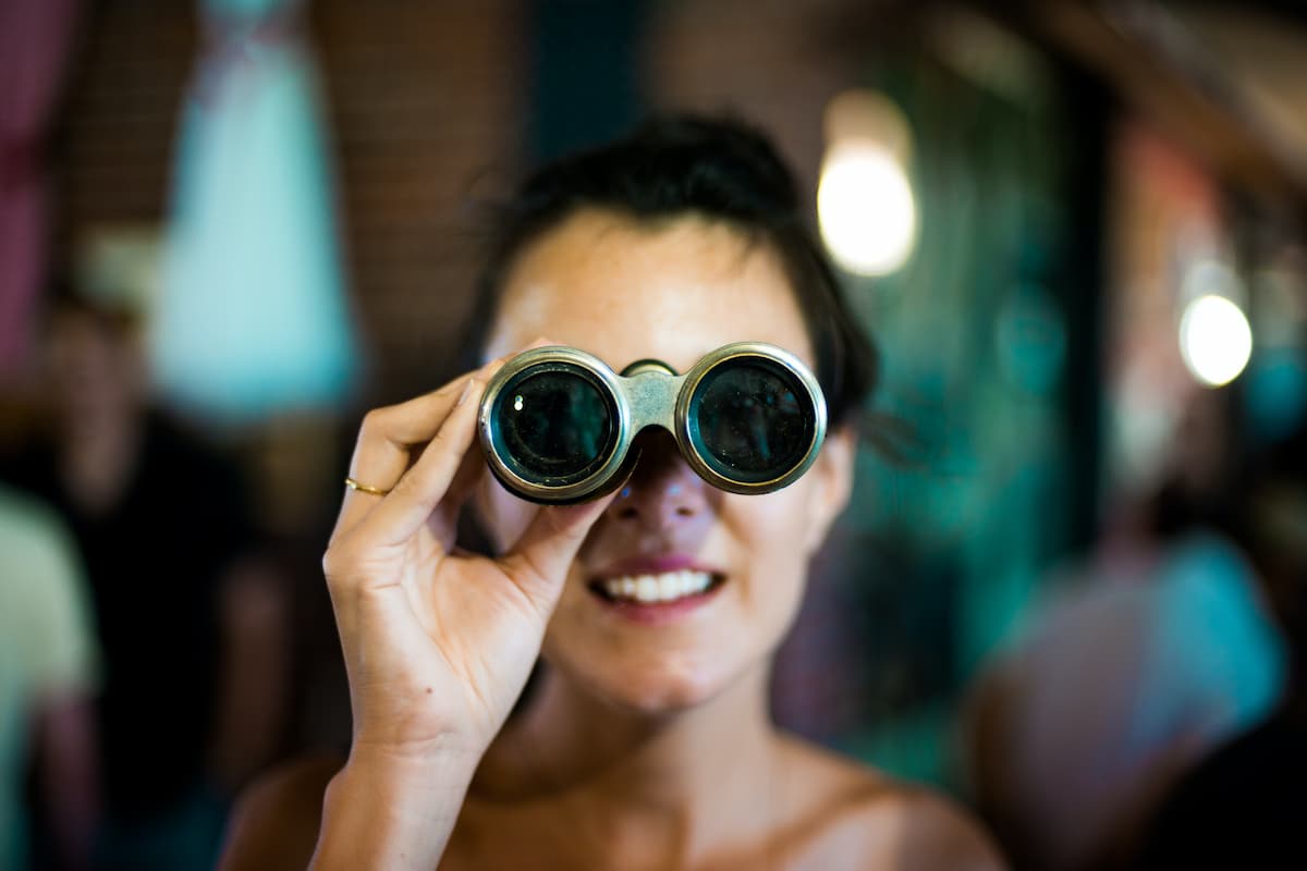 A woman using binoculars on a blurred background. 