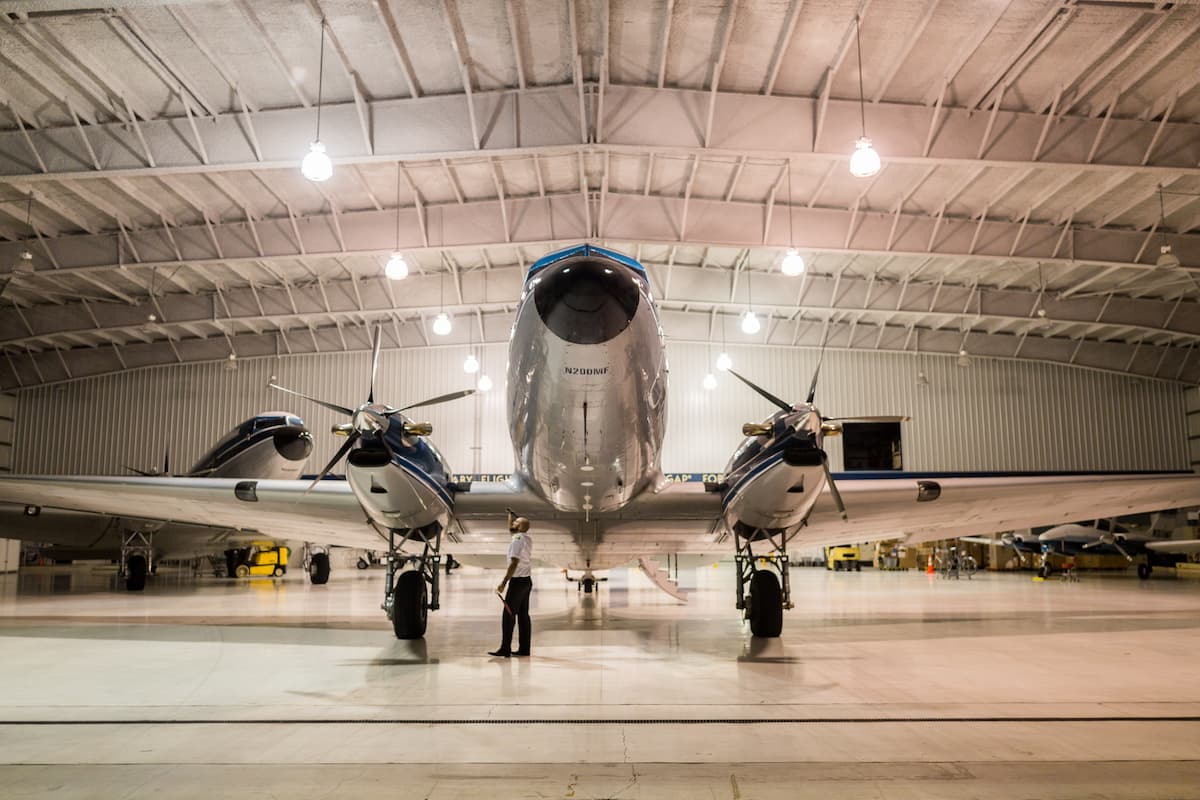 A man inspecting the gray airplane inside the hangar.