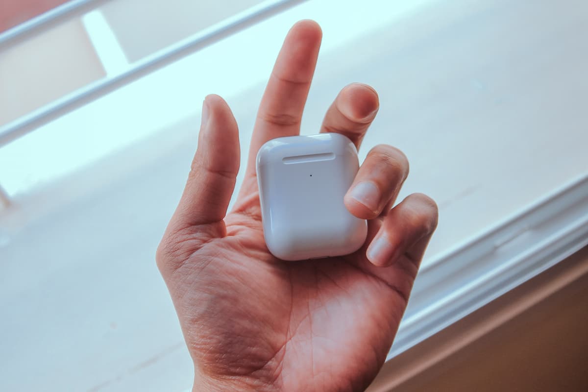 Close-up photo of a person holding AirPods.