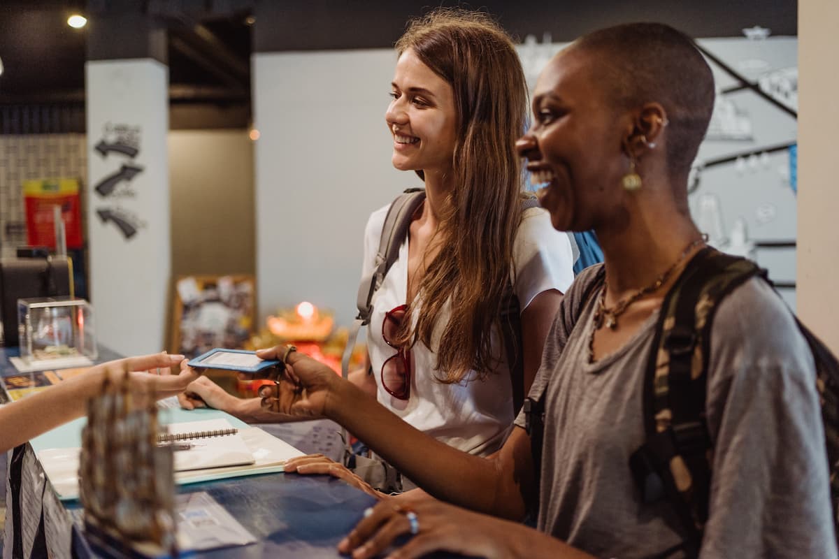 Two women receiving a hotel room card at the reception desk. 