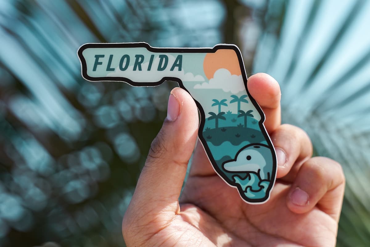 A person's hand holding a Florida magnet.
