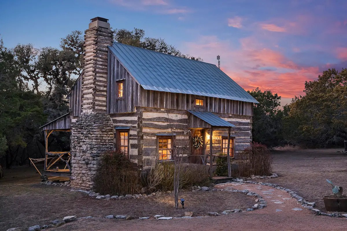 The exterior of Peach Log Cabin with its lights on during sunset. 