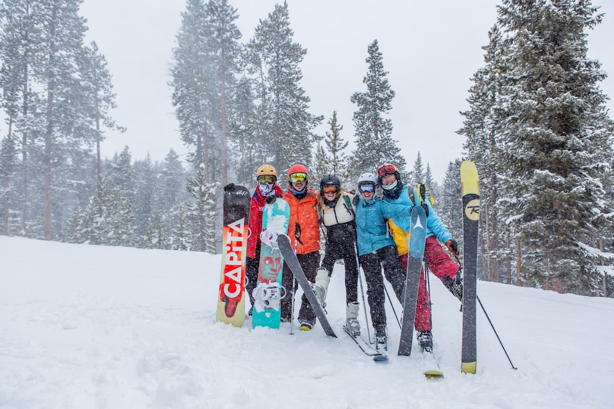 A group of people taking pictures together while holding their skis. 