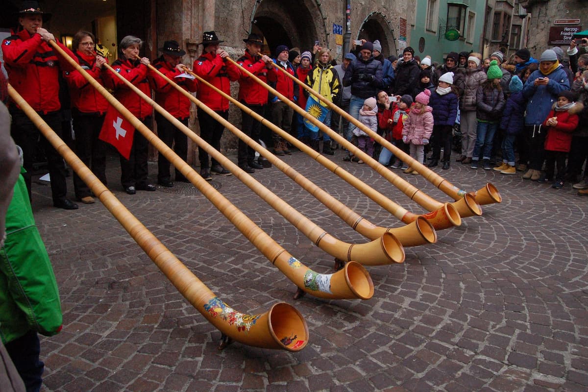 People playing alphorn in front of many people in the street. 