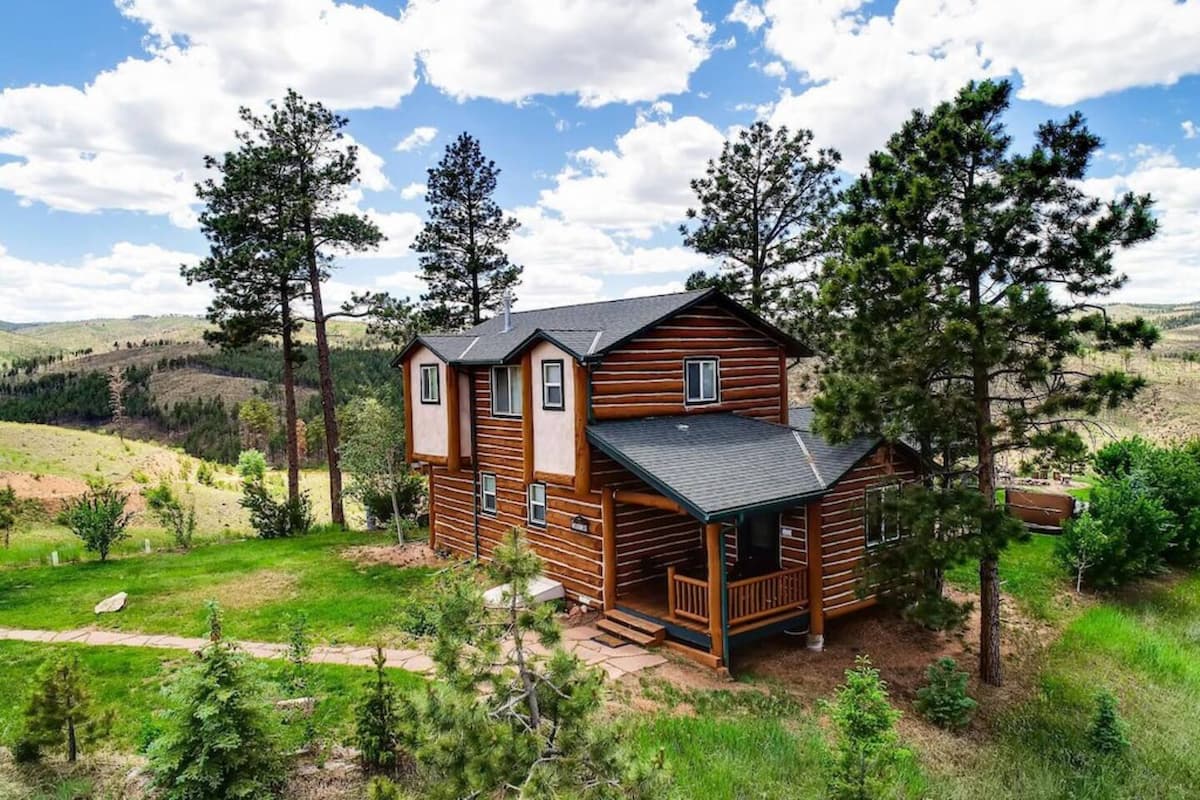 A two-story cabin at Pikes Peak Resort surrounded by trees. 