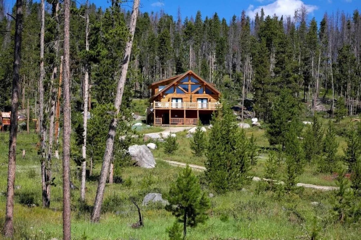 A view of the Secluded Log Cabin surrounded by tall trees.
