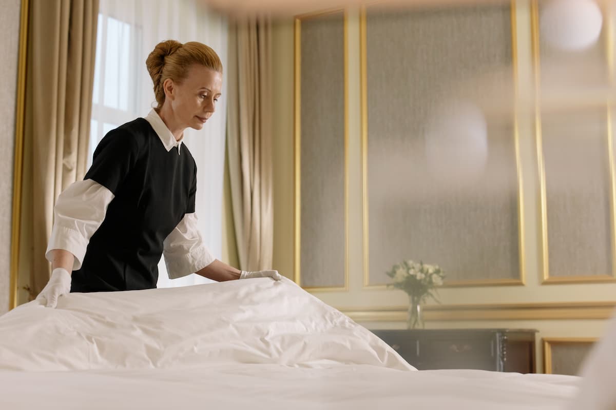 A woman hotel housekeeper fixing the bed.