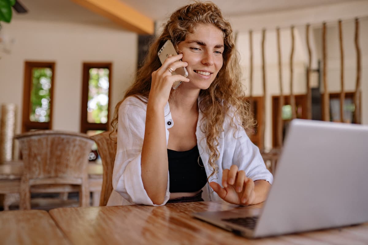 A woman sitting in front of a laptop while talking on the phone.