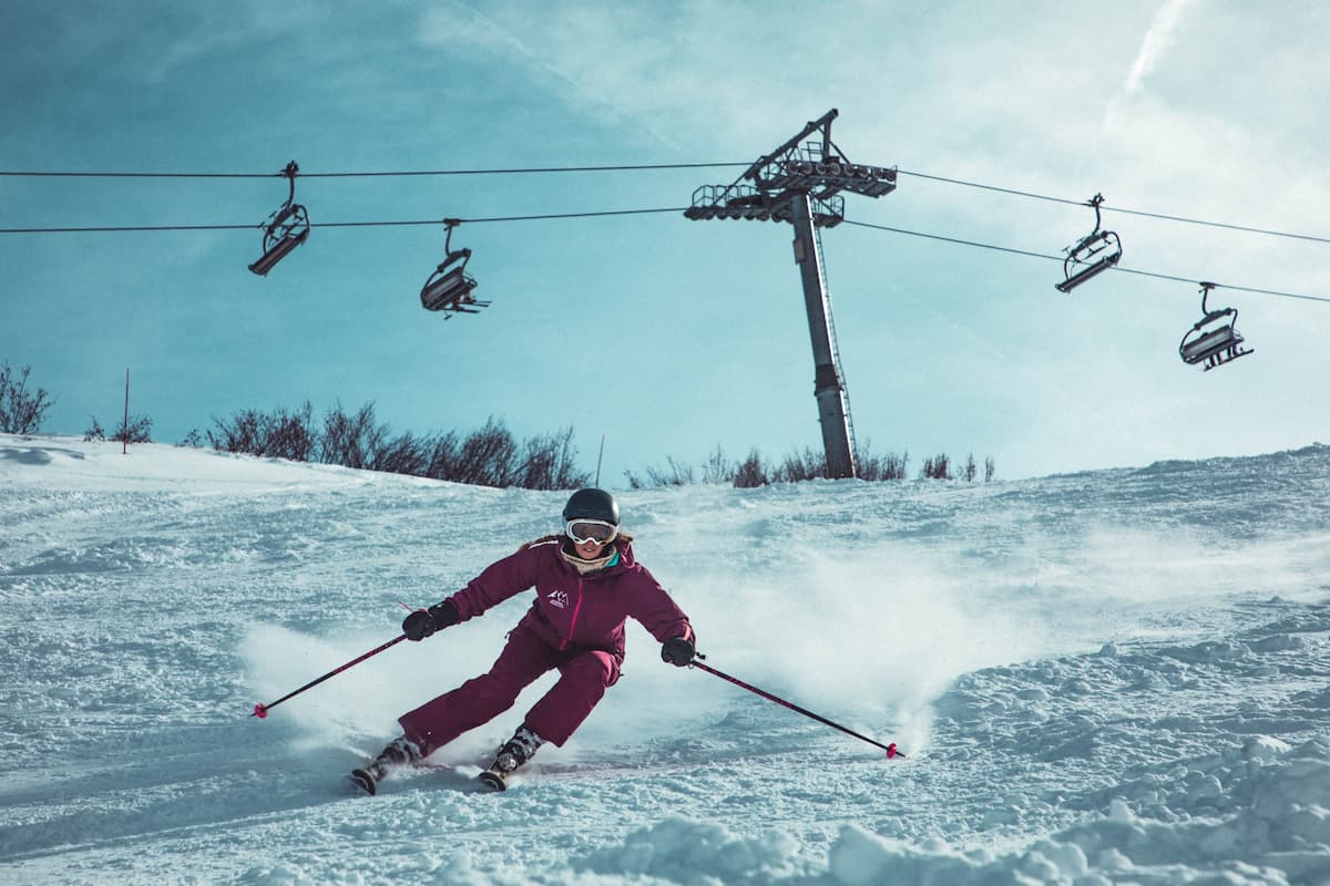 A woman skiing and ski cable cars behind her. 